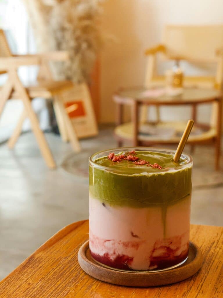 Strawberry matcha latte with layers of matcha, strawberry, and red bean toppings in a glass mug.
