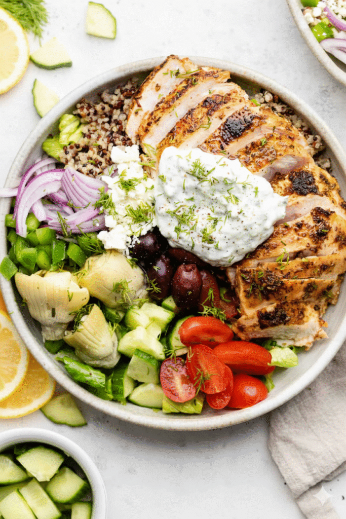 Delicious Greek Chicken Bowls topped with fresh vegetables and feta cheese INGR