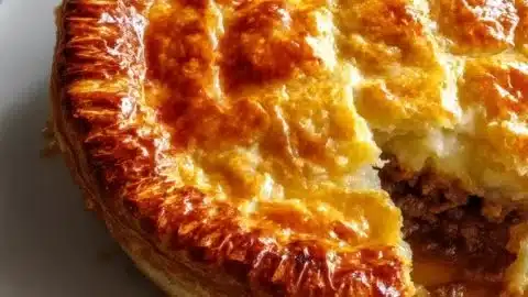 Warm Baked Traditional Scotch Pie 1 Warm baked traditional Scotch Pie on a rustic wooden table.