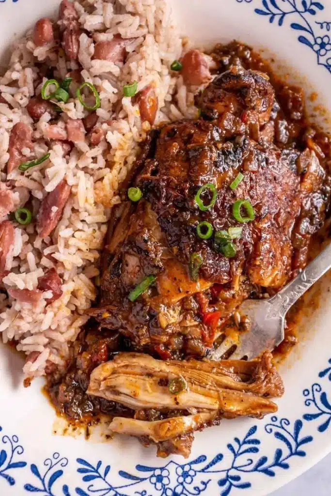 Delicious plate of authentic Jamaican Brown Stew Chicken garnished with vegetables.