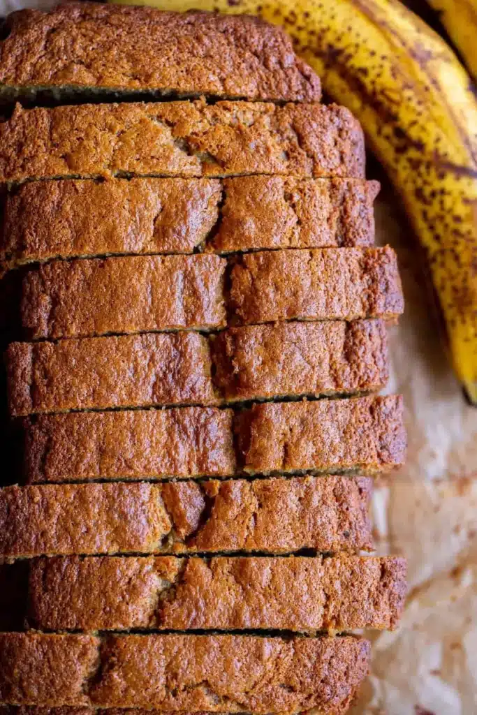Deliciously moist banana bread with ripe bananas on a wooden cutting board