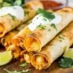 Crispy Chicken Taquitos 2 Crispy chicken taquitos served on a plate with fresh toppings