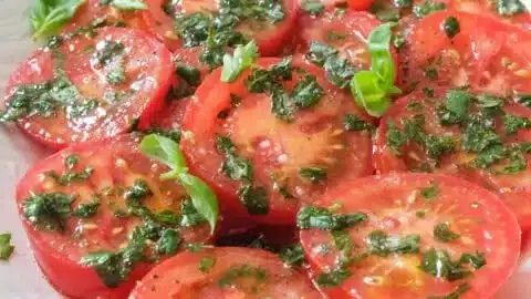 A vibrant marinated tomato salad showcasing ripe tomatoes and fresh herbs.