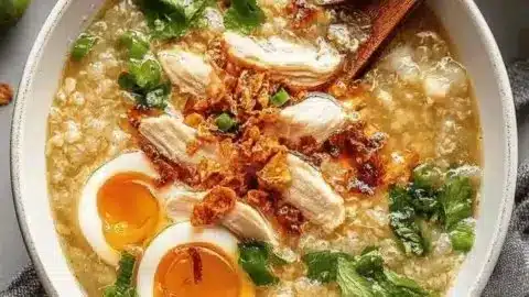 Bowl of nourishing Chicken Congee topped with green onions and herbs