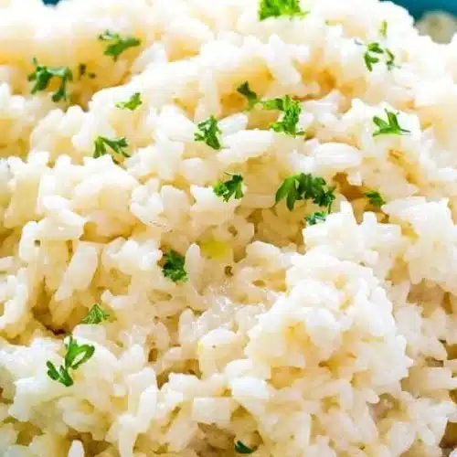 Bowl of creamy Parmesan rice garnished with herbs.