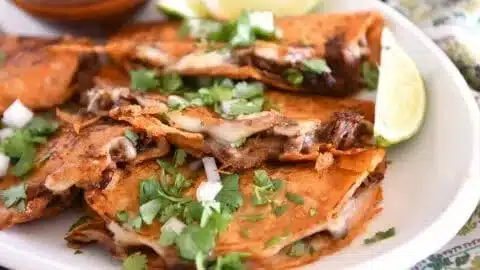 Delicious slow cooker birria tacos served with cilantro and onions.