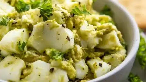 Creamy avocado egg salad served in a bowl with fresh herbs.