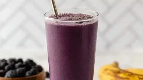 Healthy blueberry banana smoothie in a glass with fresh berries and banana slice