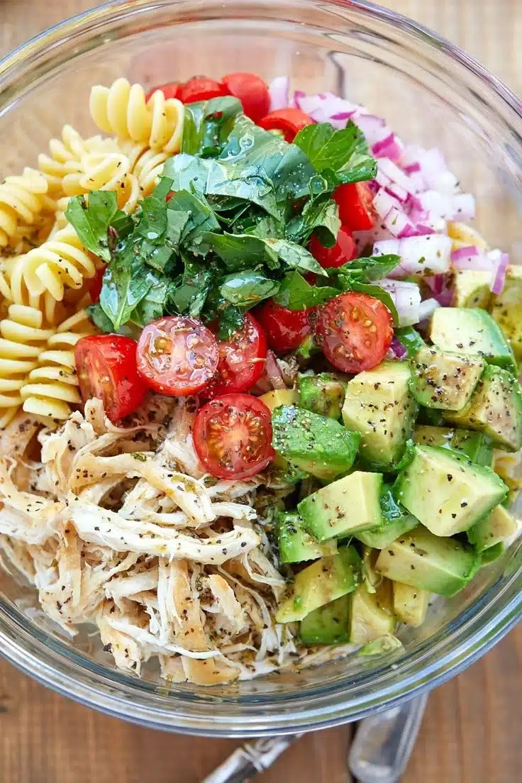 Healthy chicken pasta salad with vegetables and dressing on a plate.
