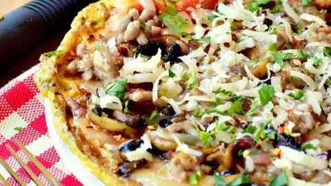 Slice of Keto Breakfast Pizza topped with eggs, cheese, and vegetables