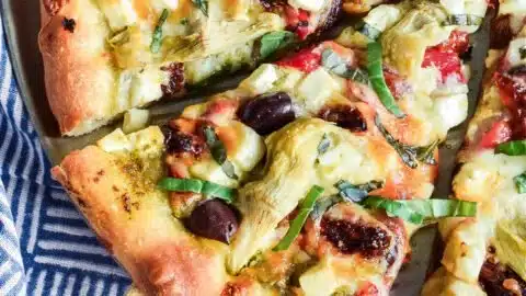 Delicious slice of Mediterranean pizza with fresh toppings and herbs.
