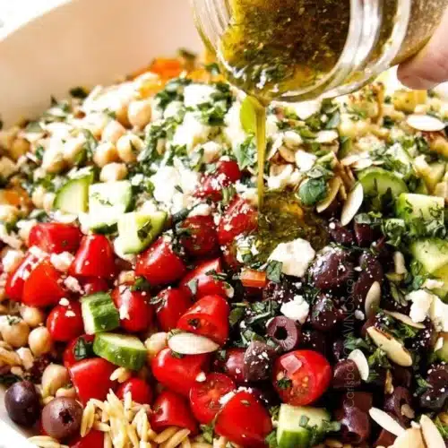 A colorful bowl of Orzo Pasta Salad with fresh vegetables and herbs