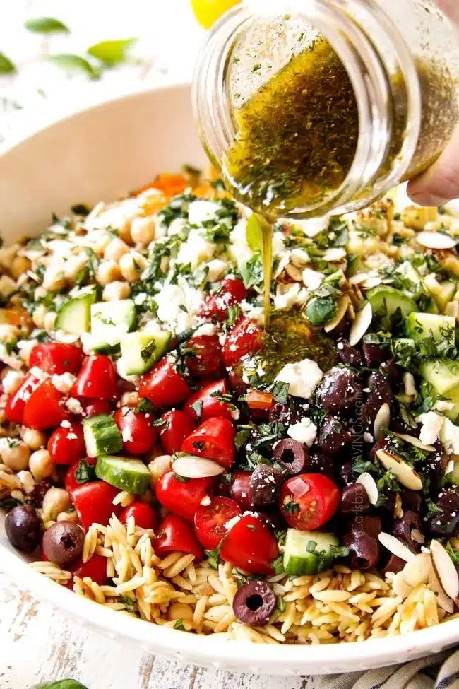 A colorful bowl of Orzo Pasta Salad with fresh vegetables and herbs