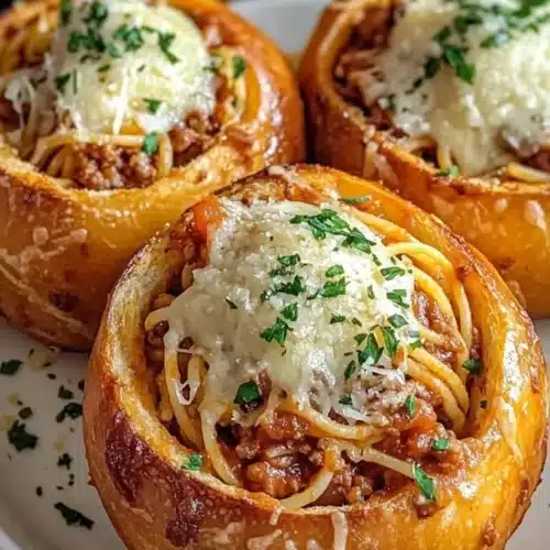 Delicious spaghetti garlic bread bowls filled with pasta and topped with herbs