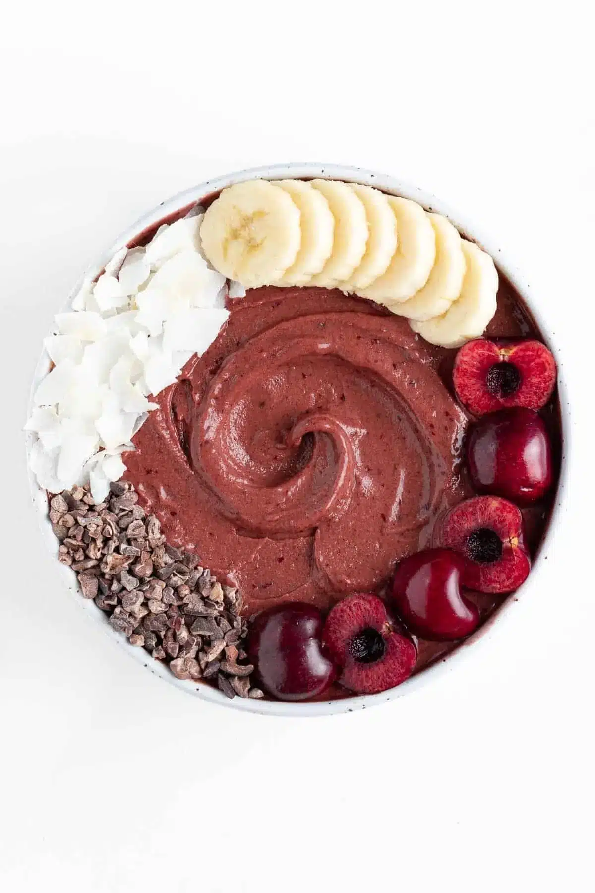 Chocolate cherry smoothie bowl topped with fresh cherries and cocoa nibs