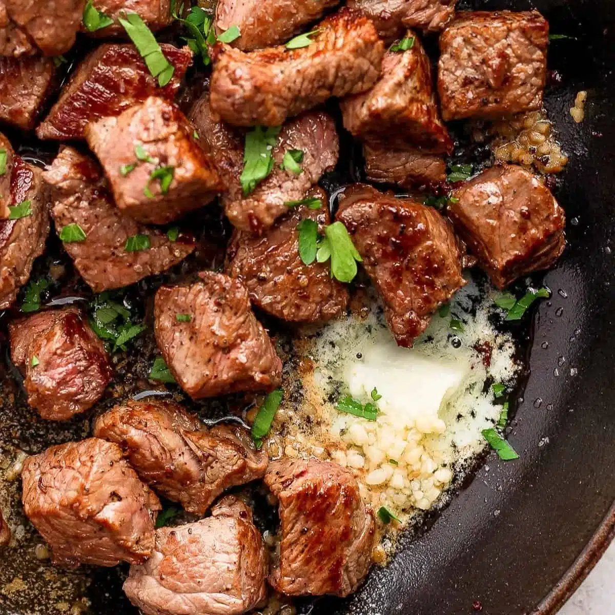 Delicious garlic butter steak bites served on a plate with herbs